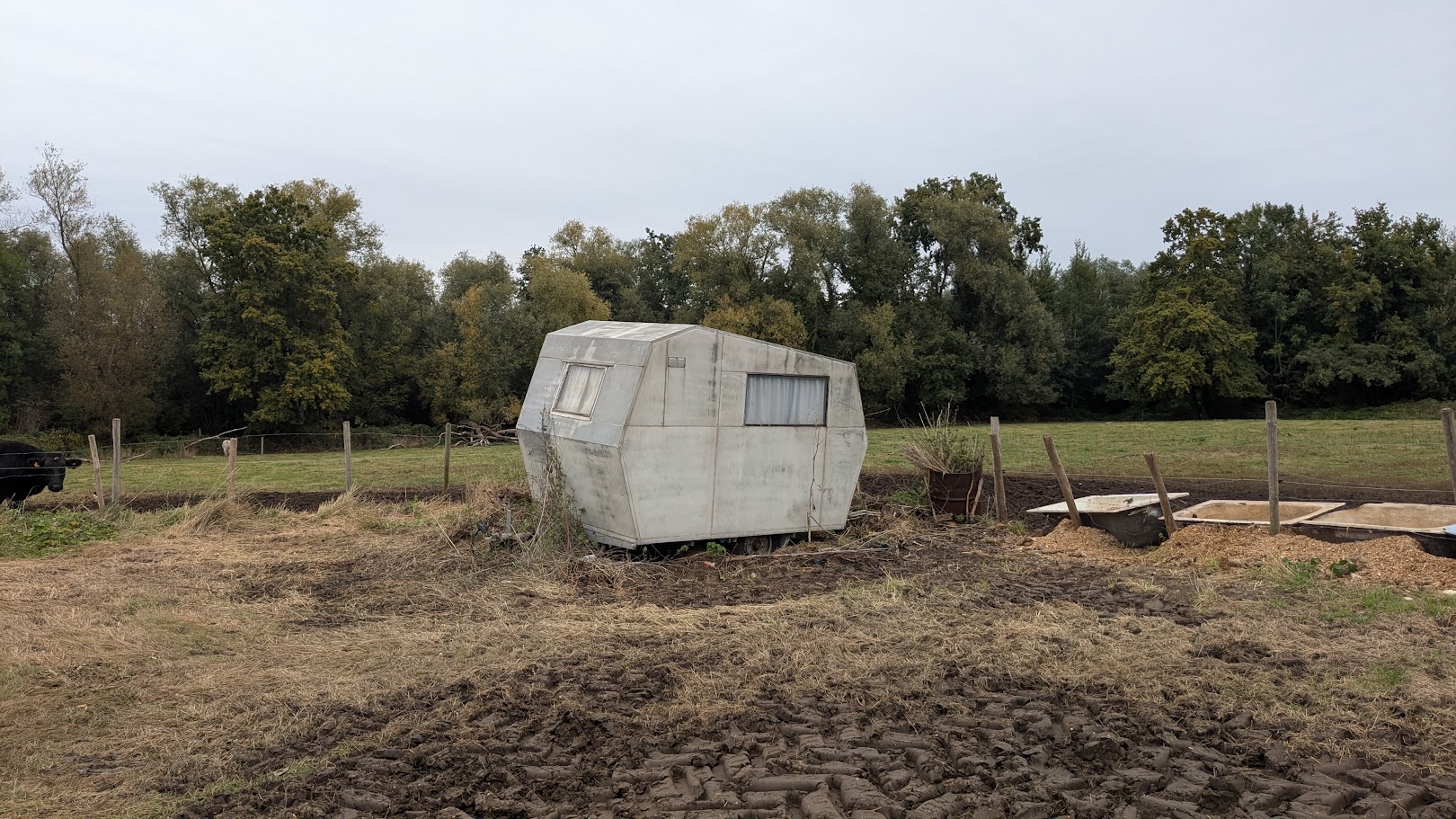 Documentair narratief van een vervallen retro caravan in een open weiland, focus op de textuur van verweerd materiaal en de melancholische schoonheid van vergankelijkheid.
